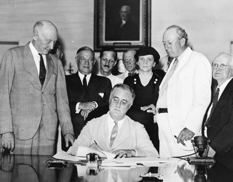president Franklin D. Roosevelt signs bill into law, flanked by others